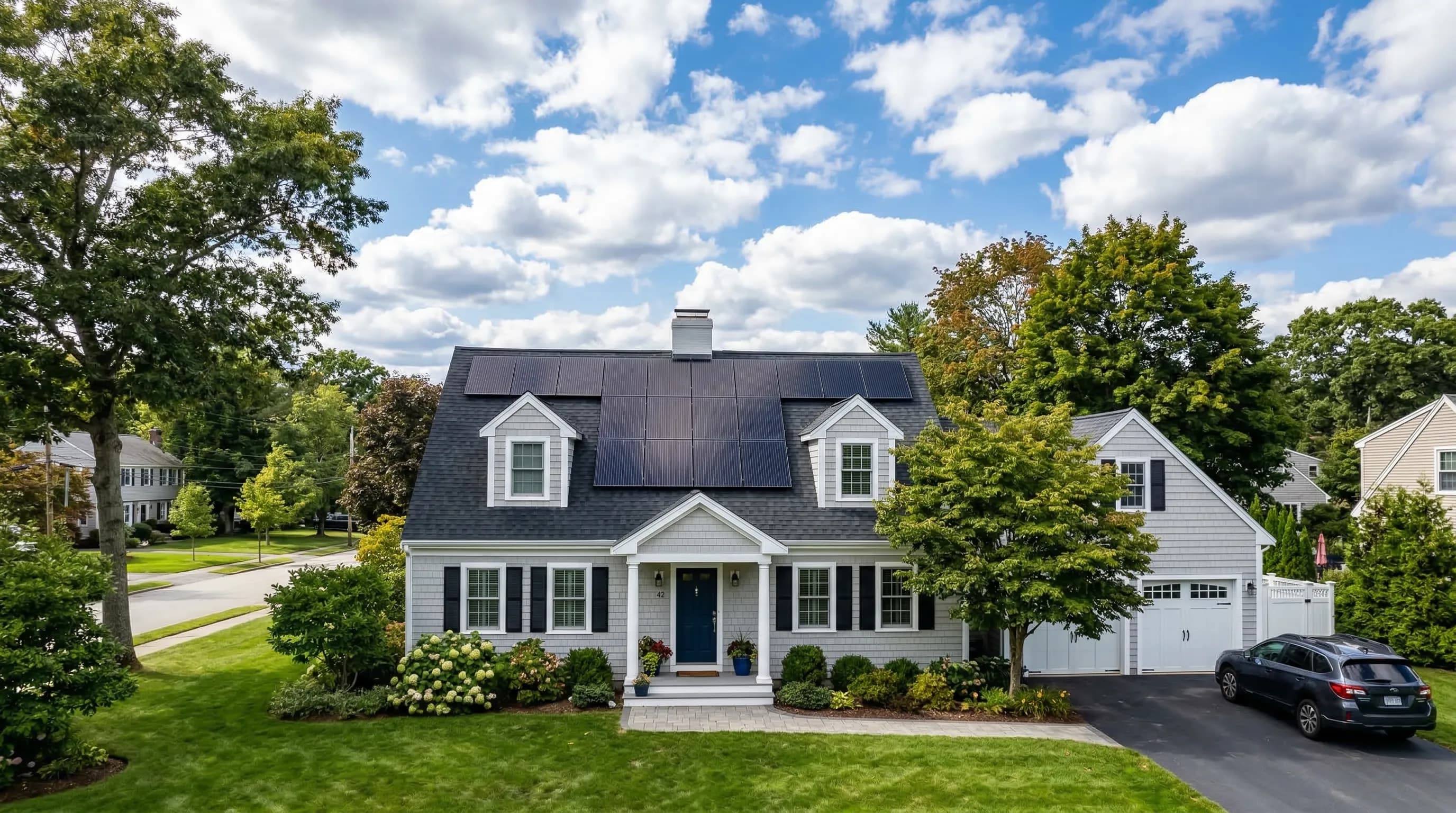 Massachusetts Cape Cod style home with solar panels installed under a blue sky