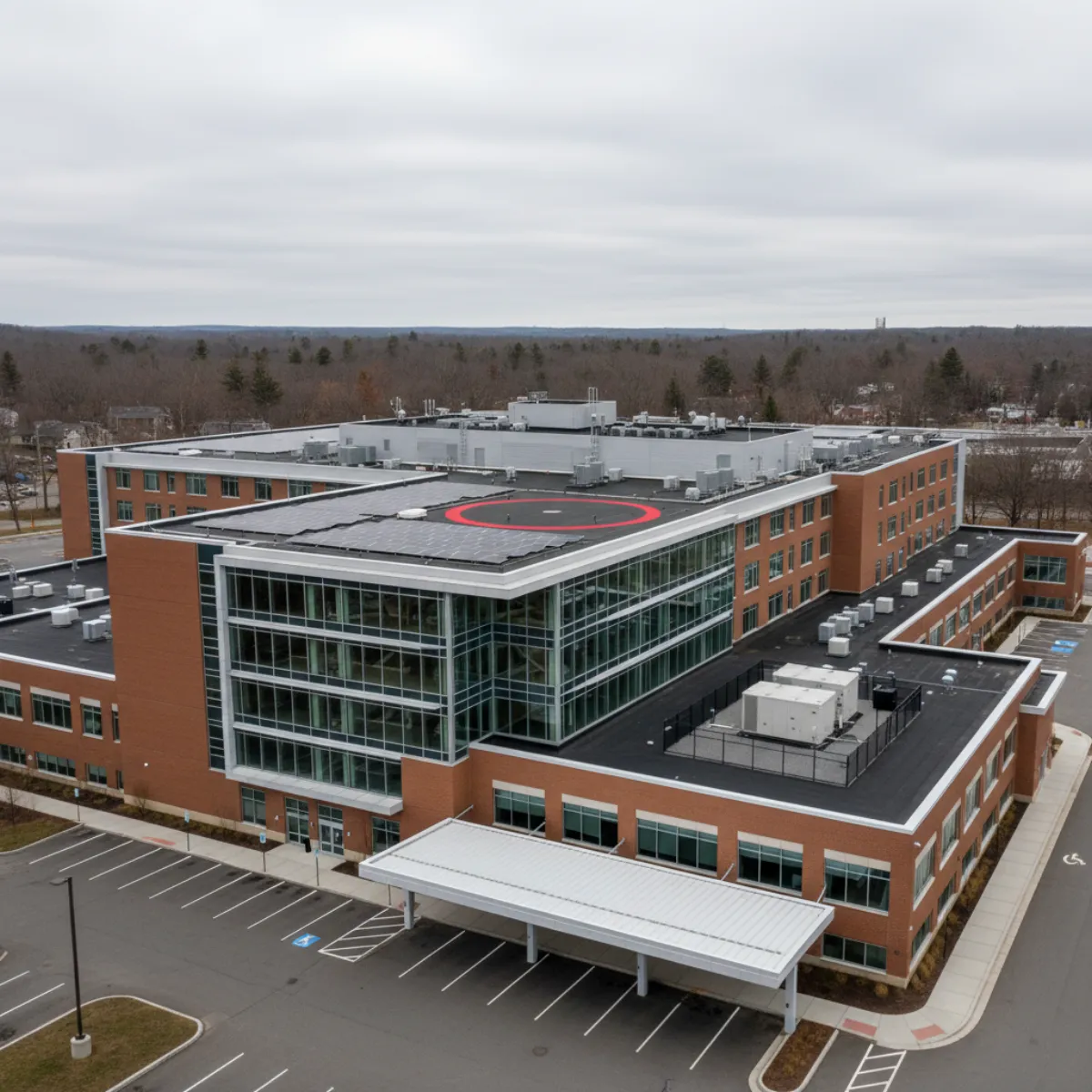 Massachusetts community hospital with rooftop solar array adjacent to helipad and HVAC equipment, battery enclosure visible at ground level